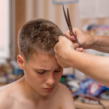 Bir çocuğun saçını kesmek, kuaföre gitmeden karantina ve koronavirüs salgını yüzünden evdeki genç adam..