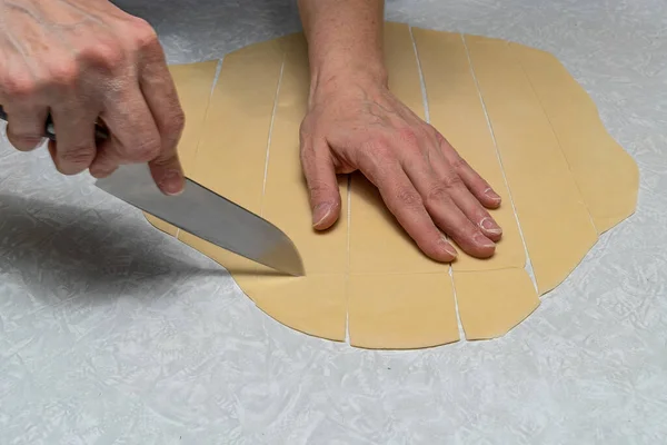 Et suyunda pişirmek için kare şeklinde pişirilen el yapımı hamurlar, merdaneyle sarılmış ve bıçakla kesilmiş..