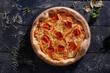Salamlı ve dolmalık biberli pizza. Koyu ahşap arka plan manzaralı.