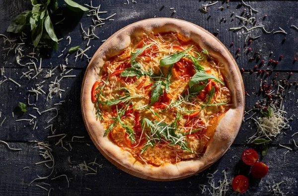 Domatesli pizza ve roka koyu ahşap arka plan manzaralı.