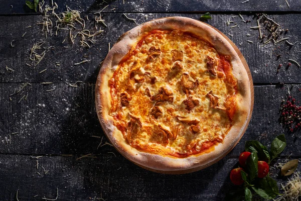 Siyah ahşap arka planda izole edilmiş Chanterelli pizza.