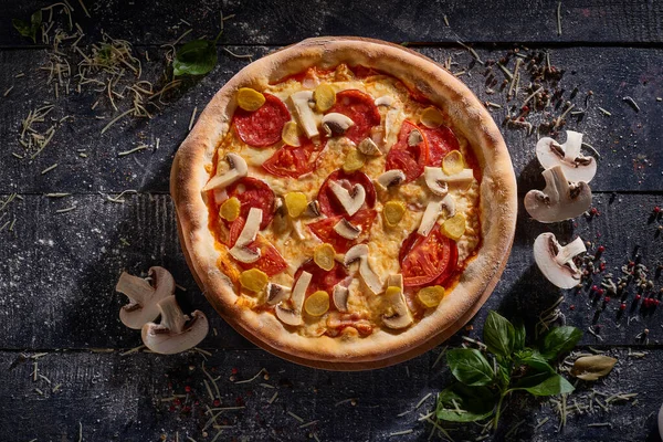 Mantarlı ve domatesli pizza. Koyu ahşap arka plan manzaralı.