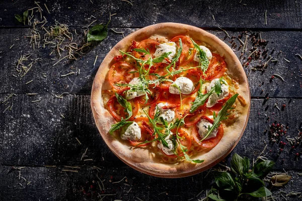Stracciatella ve roka içeren pizza koyu ahşap arka plan görünümünde izole edilmiş.