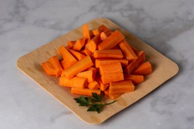 Havuçlar bambu tabakasında büyük parçalara bölünmüş mermer zemin üzerinde - sağlıklı yeme konsepti