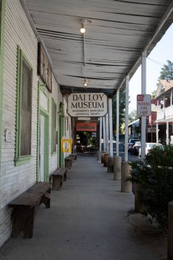 Walnut Grove, California, ABD, 27 Ağustos 2022 - Locke 'ta kaldırımda Dai Loy Müzesi ve Müzesi açık tabelanın olduğu tabela, eski banklar, sokağa park edilmiş arabalar ve kaldırımda yürüyen kimse yok; 