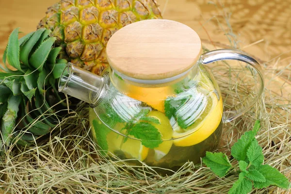 Çaydanlık şeffaf bardakta samanlıkta, ananas, nane, portakal, bal, meyve çayının yanında.