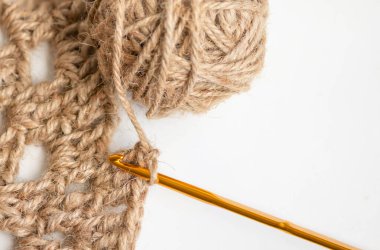Gold crochet needle plug on the work piece with crochet yarn, jute. clipart