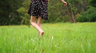 Unrecognizable young child walking on the grass barefoot. Concept of freedom and enjoying one s life. Tracking real time .4k