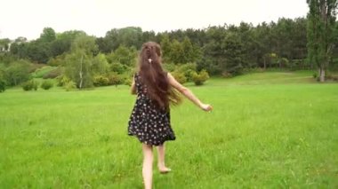 Girl run in field on green grass. Happy child plays and dream. Girl in flower garden.Happy child run towards dream on green grass. Girl playing on flower field in garden.Children fun and joy in summer