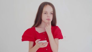 the beautiful, happy little girl looks at the phone, has an idea, then types. High quality 4k footage