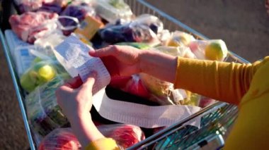 Endişeli kadın marketten alışveriş yaptıktan sonra gazete fişini kontrol ediyor. Covid-19 küresel ekonomi finansal kriz konsepti, para tasarrufu. Yiyecek ve market alışverişi. Yüksek kalite 4k görüntü