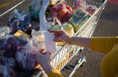 Kadın alışveriş merkezinden alışveriş yaptıktan sonra alışveriş arabasındaki Sevgili Miktar faturasını kontrol ediyor. Gıda fiyatlarında artış. Yüksek kalite 4k görüntü