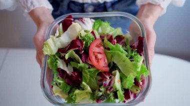 Sağlıklı beslenme, diyet ve insanların konsepti. Evde salata kasesi gösteren genç kadın ellerine yakın çekim. Yüksek kalite 4k görüntü