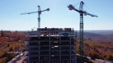 Gökdelen inşaatı ve mavi gökyüzünde vinçleri olan yeni daireler. Yeni bir yerleşim yerinde yeni bir ev. Şehir merkezinde inşaat. Beton bina inşaat sanayi bölgesi