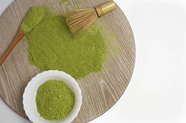 Kibrit, beyaz bir kasede yeşil çay tozu ve ahşap tabanlı bambu çırpısı. Üst Manzara. Kopyalamak için boşluk.