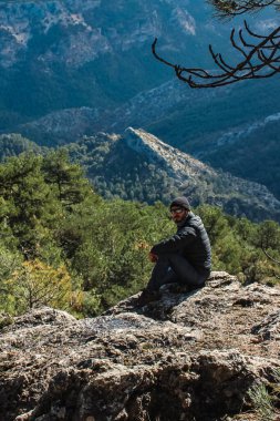 Beyaz adam Sierra de Cazorla 'da dağın tepesinde oturuyor. Arka planda dağların manzarası var..