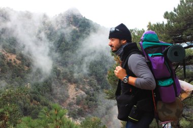 Sırt çantalı beyaz adam dağın zirvesine ulaştıktan sonra manzarayı gözlemliyor. Macera, doğa, seyahat, vahşi, spor, sağlık ve dağ kavramı.