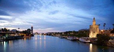Sevilla 'daki Guadalquivir nehrinin panoramik gece manzarası.