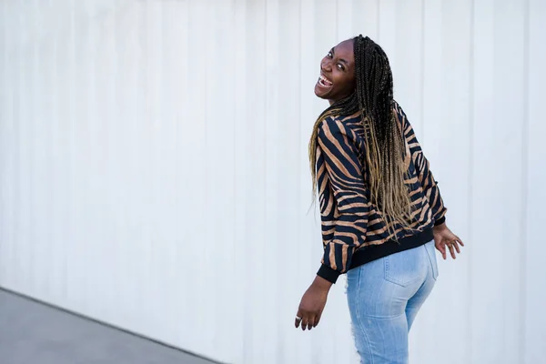 Beautiful African American woman has fun in the city. Horizontal shot, back view.