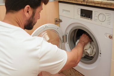 Çamaşır yıkayan adam. Ev işi kavramı. Elektrik tüketimi ve enerji tasarrufu kavramı. Yan görünüm.