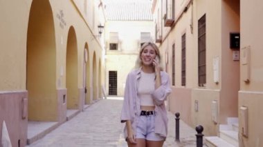 Hevesli sarışın kadın sokakta yürürken cep telefonuyla konuşuyor. Hareketli çekim. kalite 4k görüntü