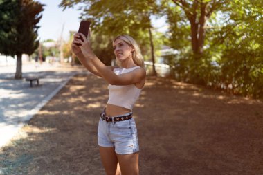 Parkta selfie çeken sarışın bir kız. Kopyalama alanı olan. Yüksek kalite fotoğraf
