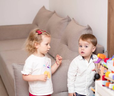 Sarışın çocuklar, kız ve erkek, beyaz ırk evde oynuyorlar. Yumuşak odaklanma. Yakın plan..