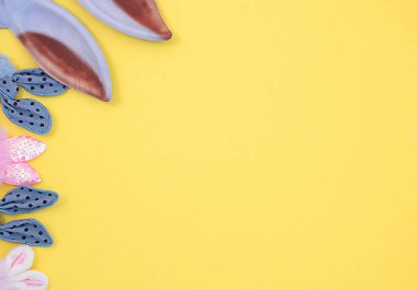 Sarı arka planda pembe ve mavi renkli tavşan kulakları. Paskalya konsepti.