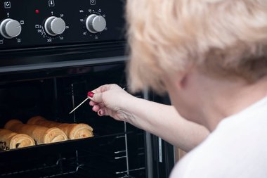 Yiyecekler. Bir kadın fırında haşhaş tohumuyla çörek pişiriyor. Yumuşak odak