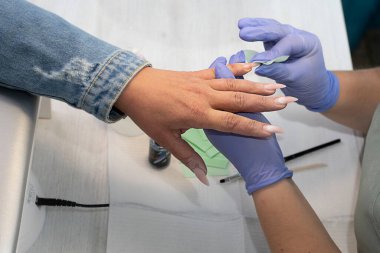Güzellik ve özen. Güzellik salonunda uzun tırnakları olan bir kız manikür ustasında bir düzeltme yapıyor. Yakın plan. Yumuşak odaklanma. Kavram.