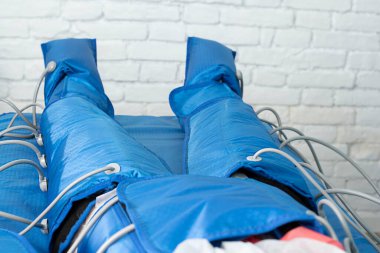 Güzellik salonunda mavi tulumlu pressooterapi prosedürü. Modern lenfatik drenaj masajı. Yakın plan. Yumuşak odaklanma. Sağlık ve güzellik kavramı..