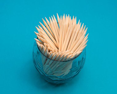 Eşyalar. Kavram. Turkuaz arka planda cam bir fincanda manikür için turuncu tahta çubuklar. Yakın plan. Minimalizm. yumuşak odak.