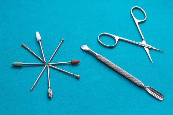 Items. Layout of professional metal manicure tools on a turquoise background. Close-up. Soft focus. Concept.