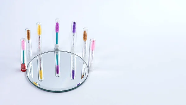 Items. Layout of multi-colored cosmetic professional brushes for eyebrows and eyelashes on a white background with a reflection in the mirror. Concept. Soft focus. copy space.