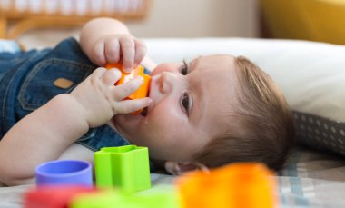 Mutlu ve neşeli 8 aylık bebek evde renkli tuğlalarla oynuyor.