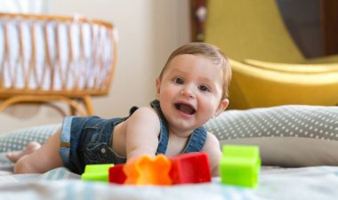 Mutlu ve neşeli 8 aylık bebek evde renkli tuğlalarla oynuyor.