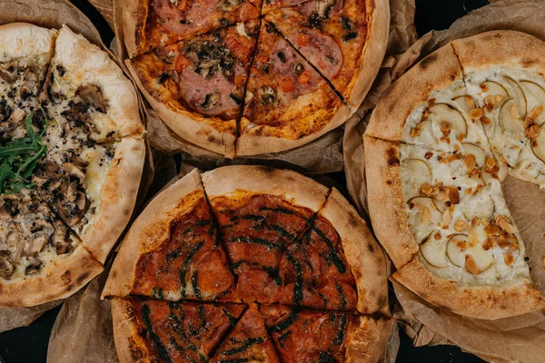 Parşömen kağıdında servis edilen dört farklı pizza. Et ve vejetaryen.