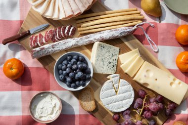 Tahta bir masada peynir, meyve ve sebze.