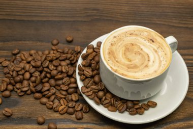 Bir fincan kapuçino ve kızarmış kahve çekirdeği.