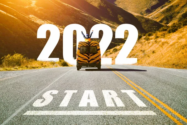 Gelecek yıl konseptinde yeni yıla başlamak için 2022 yılına başlayın. 2022 'de yazılmış metne giden asfalt yolun kaplan desenli turlu mini minibüs arabasıyla soyut görüntüsü. Çin Yeni Yılı.