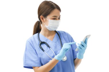 Cerrahi maske takan genç Asyalı kadın hemşire cep telefonu danışmanlığına bakıyor. Hasta sağlığı sorununa talimat veriyor ve teşhis koyuyor..