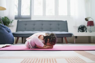 Asyalı kız oturma odasında yoga yaparak egzersiz yapıyor..