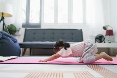 Asyalı kız oturma odasında yoga yaparak egzersiz yapıyor..