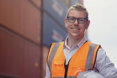 Portrait of Caucasian supervisor standing in front of container yard at the background.