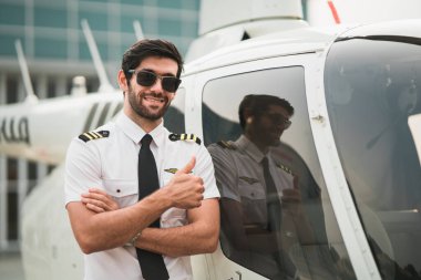 İyimser helikopter pilotunun portresi uçakla durup kameraya bakarken gülümsüyor. Dışarıdaki hangarda yakışıklı ve kendinden emin bir adam var. Uçak gemisi işgali. Uçmaya hazır..