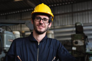 İyimser sanayi işçilerinin portresi sanayi bölgesi fabrikası, konsept imalat endüstrisi, mühendislik işçisi mesleğine güler yüzle ayakta duruyor..