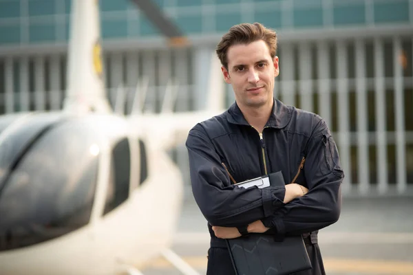 Portrait of maintenance man in uniform standing nearby aircraft and smiling while looking at camera. Optimistic helicopter inspector smile with confident at hangar outdoor. aircraft carrier occupation