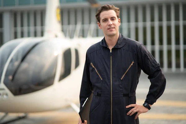 Portrait of maintenance man in uniform standing nearby aircraft and smiling while looking at camera. Optimistic helicopter inspector smile with confident at hangar outdoor. aircraft carrier occupation