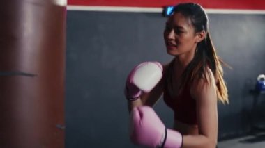 Spor salonunda Asyalı kadın boks antrenmanını yakından çek. Öfkeli kız kum torbasıyla boks yapar. Spor Dayanıklılık.