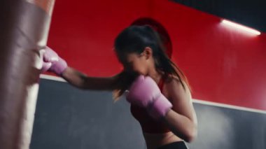 Spor salonunda Asyalı kadın boks antrenmanını yakından çek. Öfkeli kız kum torbasıyla boks yapar. Spor Dayanıklılık.
